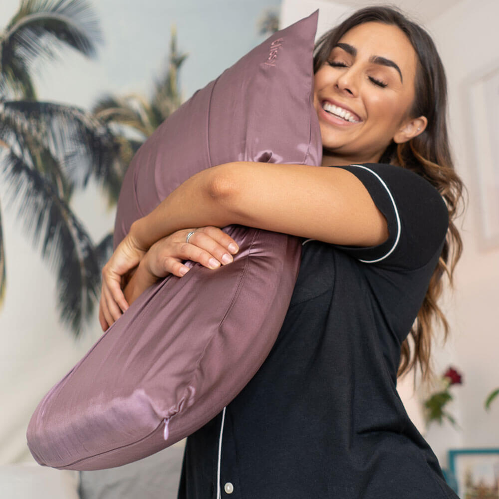 Woman hugging a pillow with Blissy mulberry silk plum pillowcase